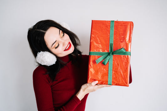 a woman in a red turtleneck is holding a red christmas box