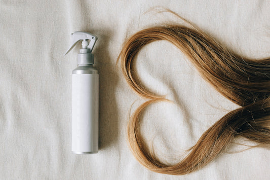 blonde long hair shaped in a heart next to a hair spray_white background