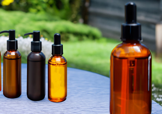 4 colored glass dropper bottles from left to right (amber, black, gold, red)